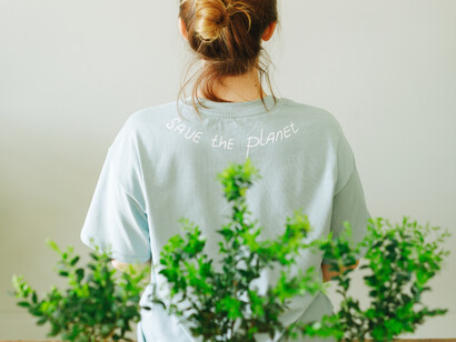 A woman wearing a save the planet t-shirt, sitting in front of three plants