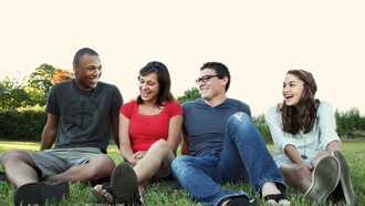 A group of platonic friends sat on the grass talking to each other 