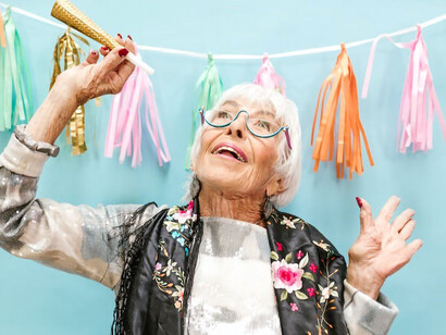 An old woman basks in the glow of her milestone birthday, radiating happiness and savoring every moment of her well-lived life
