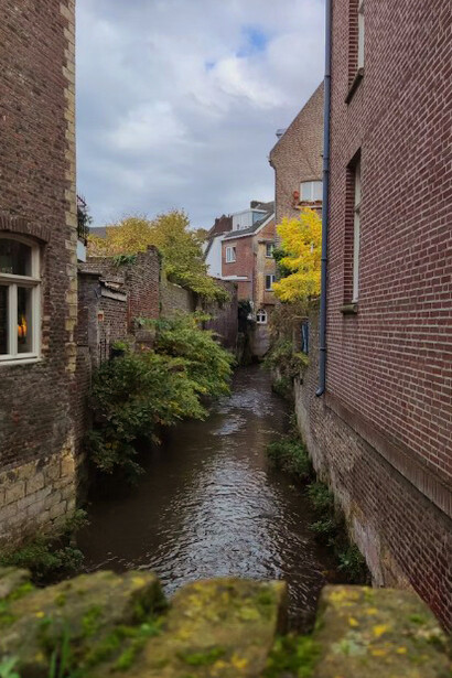 Along the river in Maastricht, a brown brick building rises among rows of houses and traditional Dutch architecture