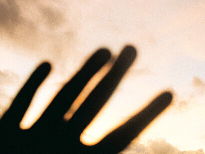 Una mano proyecta su silueta sobre un cielo iluminado, recortada por el resplandor