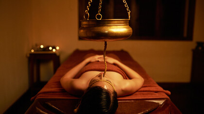 Trattamento Snehana, l'olio gocciola sulla fronte secondo uno schema ritmico