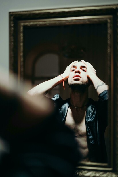 Man looking at himself in the mirror, holding his face in distress