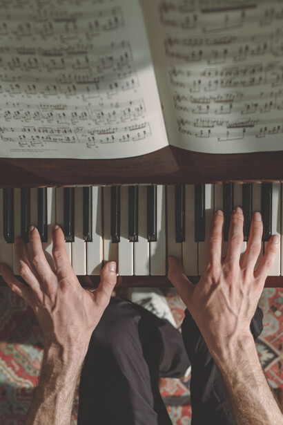 Músico lê partitura enquanto toca teclas de piano