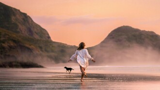 Une femme qui court sur la plage avec un chien apprécie le goût de la liberté