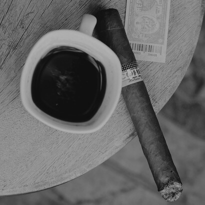 A rich black coffee and a half-smoked Cohiba cigar create a moment of indulgence, where taste and tradition meet