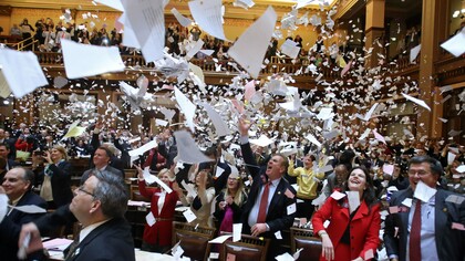 Políticos lanzando al aire sus papeles en una sede parlamentaria
