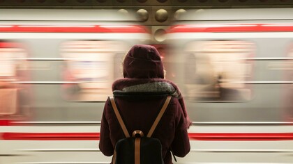 A woman standing alone in front of a fast-riding train