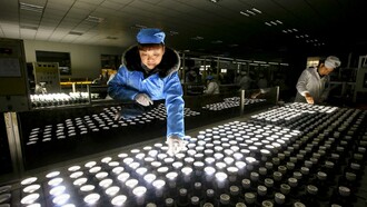 Empleados chinos trabajando en una línea de producción de bombillas de bajo consumo

