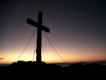 Un cruz solitaria se enfrenta al atardecer. Estas líneas despiertan una fuerza interna, una luz de esperanza