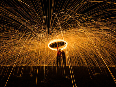 A person standing beside another person holding fire poi; universal truth and reason are the strong energy of humanity