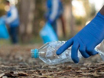 A dedicated individual collects plastic trash in a polluted park, showcasing the pressing demand for bioplastics, eco-friendly alternatives, and innovative recycling methods