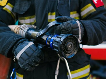 Profissional equipado com mangueira, aguardando ou se preparando para atuar. Representa a resposta que muitas vezes só acontece depois que o problema já começou