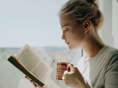 Engrossed in her book, she finds solace in the quiet, each page turning offering a refreshing escape from daily distractions