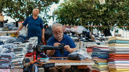A man sitting at a table, with a gun beside him and a pile of laundry nearby, Turkey