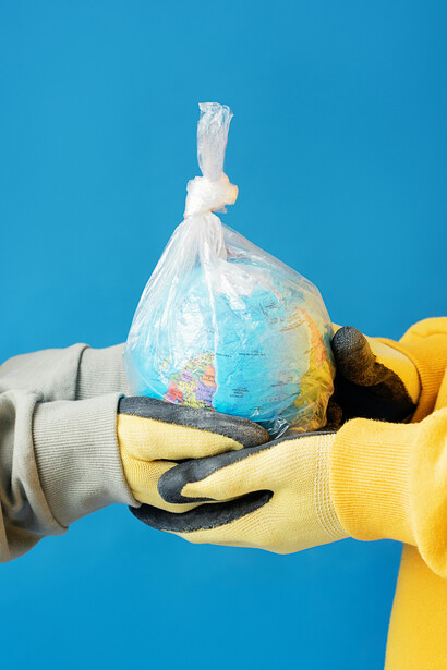 A globe encased in plastic is held in human hands