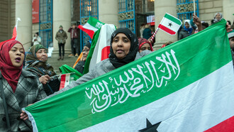 In a sea of vibrant colors, a woman proudly waves the Somaliland flag, embodying the spirit of a nation striving for international recognition and a brighter future