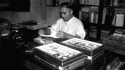 René Lichy trabajando en su estudio. A su espalda se nota parte de su extensa biblioteca. Frente a él, manuscritos y cajas conteniendo diversos lepidópteros. Foto: Atahualpa Lichy
