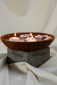 Tigela de madeira com velas acesas e pétalas
