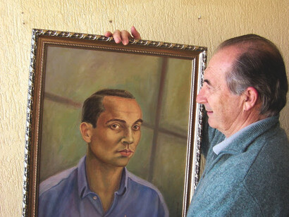 Ramón Fernández Palmeral junto al cuadro de Miguel Hernández que ilustra la portada de su libro 'El poeta del pueblo'