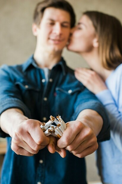 A woman kisses her boyfriend while holding a broken bundle of cigarettes