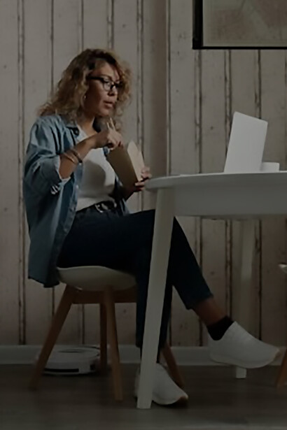 A woman sips her coffee, immersed in a video chat with another, the glow of her computer casting a warm ambiance as they share moments through the digital screen