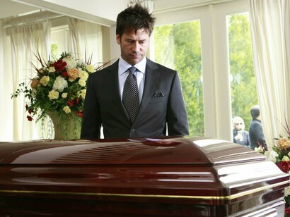 Un hombre mira con tristeza un ataud