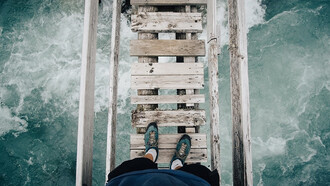 An individual standing upon a rustic wooden bridge