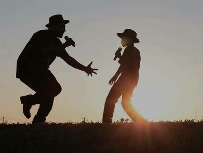 Father and son at sunset holding microphones, dialoguing and dancing all at the same time