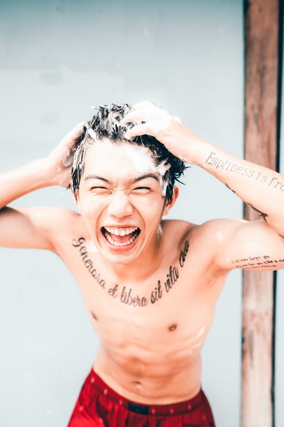 Happy man washing his hair. Those who enjoy their lives in the moment they live, are the happiest