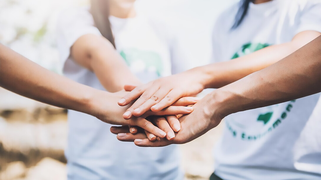 A close-up of volunteers forming a star shape with their hands, showcasing teamwork and unity