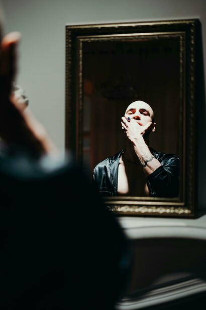 Man confronting his reflection in the mirror, hands on his face