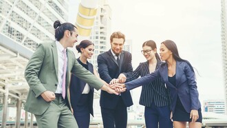 A collaborative team expressing solidarity through joined hands, symbolising the value of collective commitment