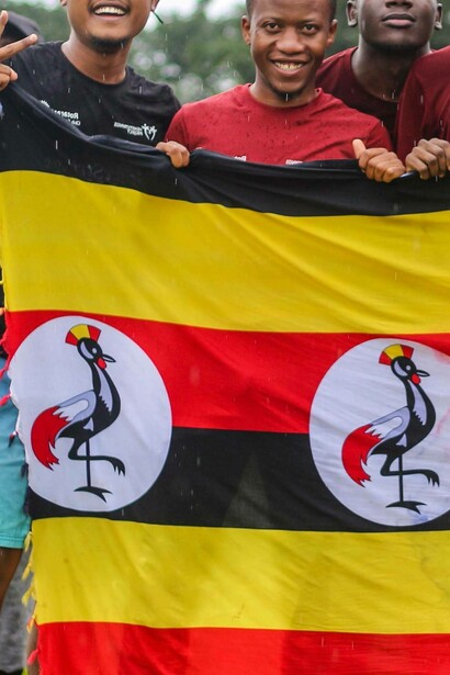 Ugandans smile while they hold national flag