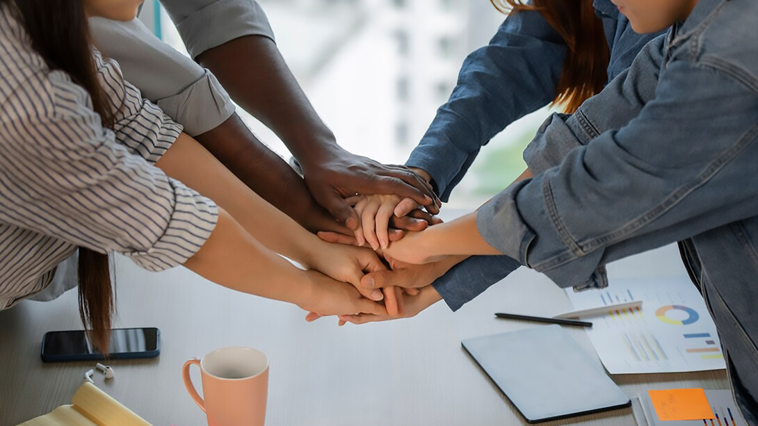 Colleagues working together, enthusiastically joining fists in a show of teamwork and collaboration
