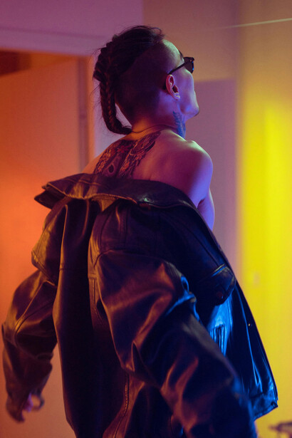A Japanese man with a traditional tattoo on his back, standing in front of a house
