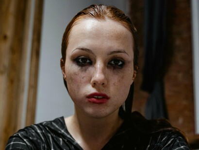 A woman with a blank stare and distant gaze reflecting profound emotional exhaustion, highlighting the emotional toll of living in a world driven by excessive ambition and insatiable desires
