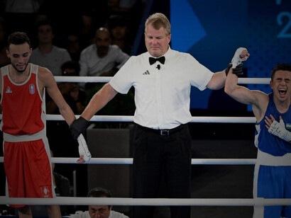 Referee Wade Peterson raises Hasanboy Dusmatov’s hand after judges declare him the winner of the men’s 51 kg gold medal bout at Roland-Garros Stadium