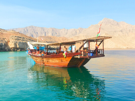 A group of tourists sailing the green waters of Musandam, Oman