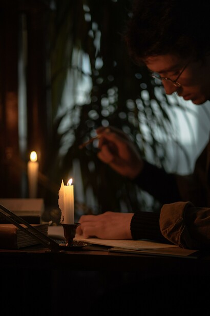 Someone writing on his desk with candle lights