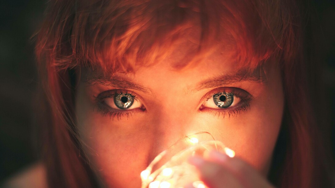 A woman holding a lightbulb to her face expressing her desire for the light