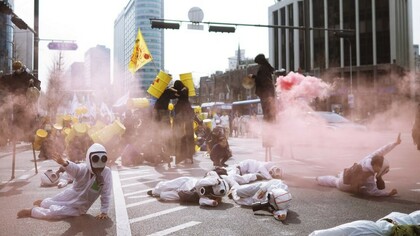 Protesters in scrub suits lie on the road surrounded by smoke during an anti-nuclear demonstration