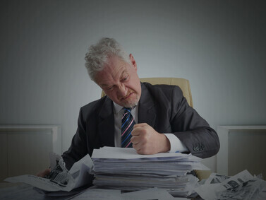 An entrepreneur at a desk, overwhelmed by government paperwork and documents