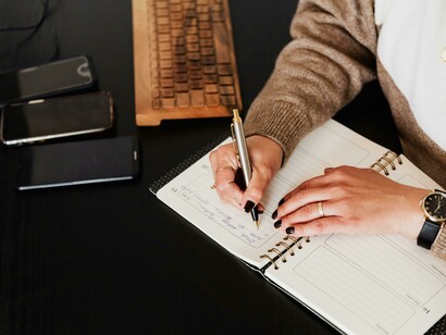 A woman writing in her diary, thoughtfully holding a pen