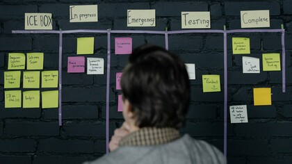 A professional reviewing a project workflow board, representing the importance of building systems that support consistent execution