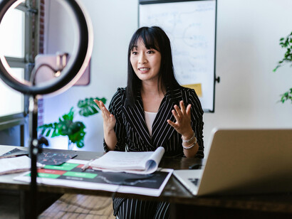 A content creator in an office setting, smiling while recording a video