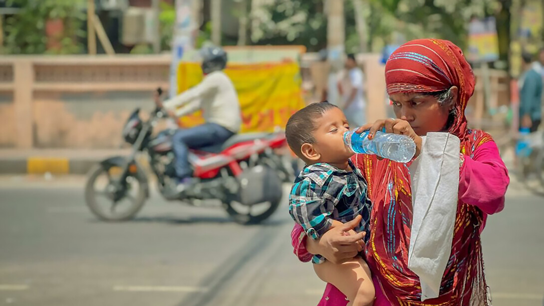 An Indian man gives his child water to stay hydrated during extreme summer heat, highlighting the risks of dehydration and heat exhaustio