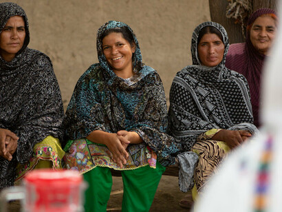 Pakistani women gathered together, smiling and hopeful, trying to break the cycle of poverty