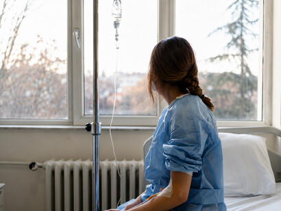 A female patient sits alone in a quiet hospital room, reflecting in silence