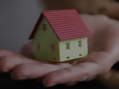 In the midst of America's housing problem and economic recession, a businessman's hand holds a symbolic tiny house savings model, reflecting the challenges and aspirations of the current real estate landscape